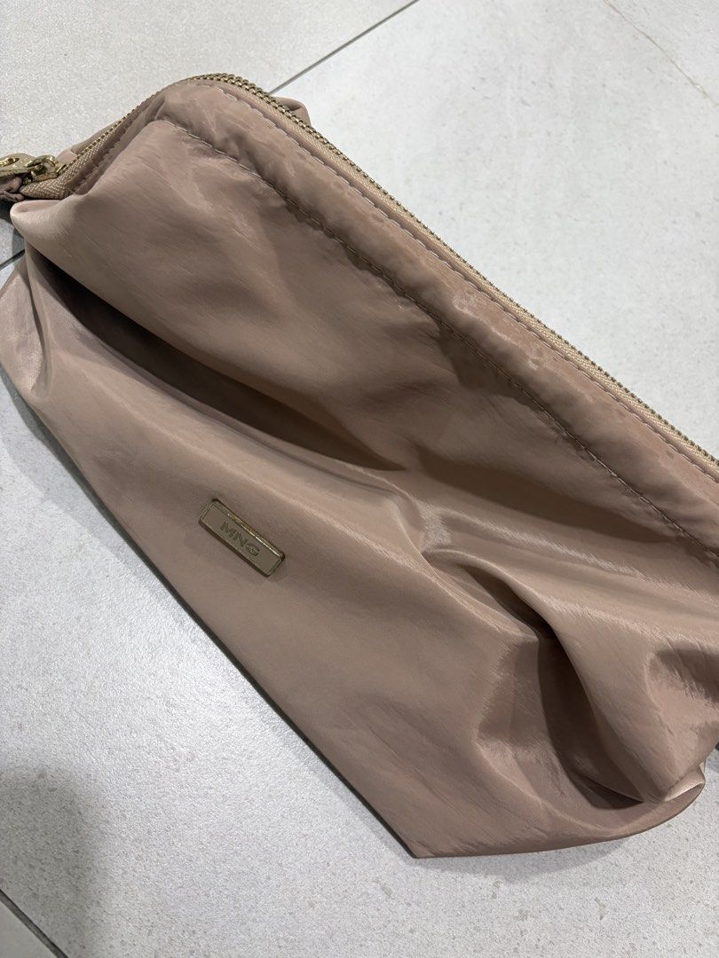 Mango MNG Beige Nylon Cosmetic Pouch Makeup Bag (Category: Purses & Pouches) located in Makati City. Submitted by citysunset (Listing ID 1465294941, Image 2). Description: Mango makeup pouch in soft pink nylon. Compact size for daily essentials. Features a small metal MNG logo plaque on the front. Zip-around closure with a gold-tone pull. Clean interior lined with polyester fabric and inner slip pockets. Lightweight material, easy to toss into a 