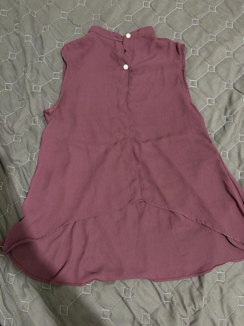 Maroon High-Low Sleeveless Blouse with Back Buttons (Category: Sleeveless) located in Pasig City. Submitted by vhasibuan (Listing ID 1465290855, Image 1). Description: - Color: Maroon - Material: Lightweight chiffon - Design: Sleeveless with a high collar and back button closure - Hemline: High-low curved hem (longer in the back) - Style: Solid color, versatile for pairing with jeans or skirts.