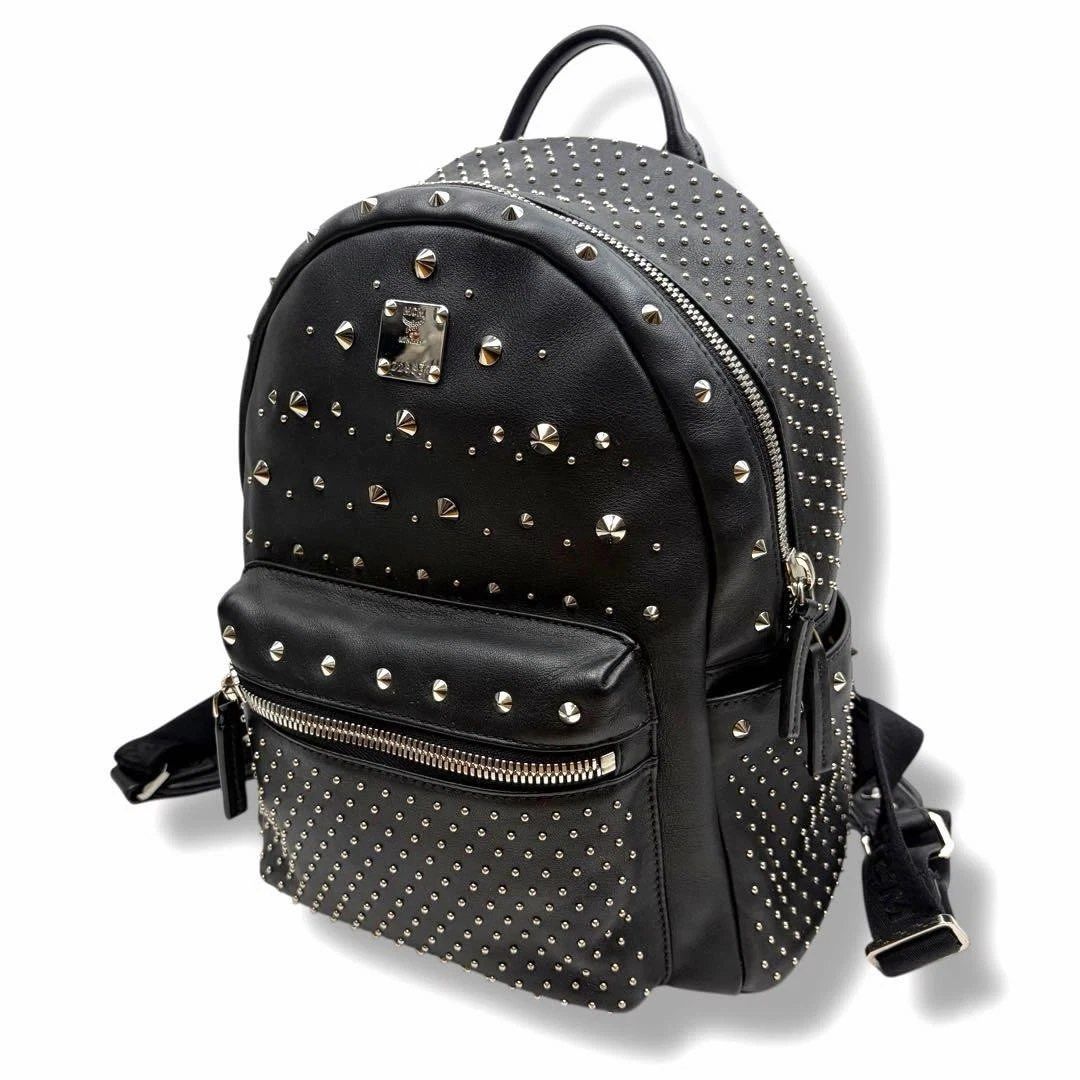 MCM Black Studded Leather Backpack (Category: Backpacks) located in Angeles City. Submitted by sheloves. (Listing ID 1465176593, Image 1). Description: - Brand: MCM Authentic - Material: Black leather with striking silver metal studs in mixed sizes - Compartments: Roomy main compartment with dual zippers and a convenient front zip pocket - Hardware: Premium silver-tone hardware with custom zipper pulls and iconic MCM front logo plaque - Straps: A