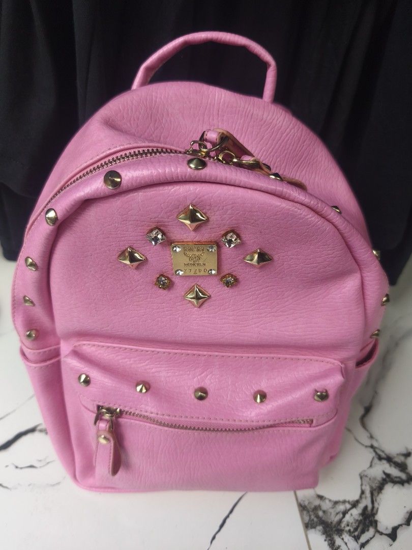 MCM Pink Studded Backpack (Category: Backpacks) located in General Mariano Alvarez. Submitted by crisshane_13 (Listing ID 1465246138, Image 1). Description: - Authentic MCM backpack in eye-catching bright pink leather - Covered in edgy metal studs and sparkling crystal embellishments - Luxurious gold-tone hardware and iconic MCM logo plates - Practical storage: main zip compartment, front zip pocket, and interior zip pocket - Comfortable top grab