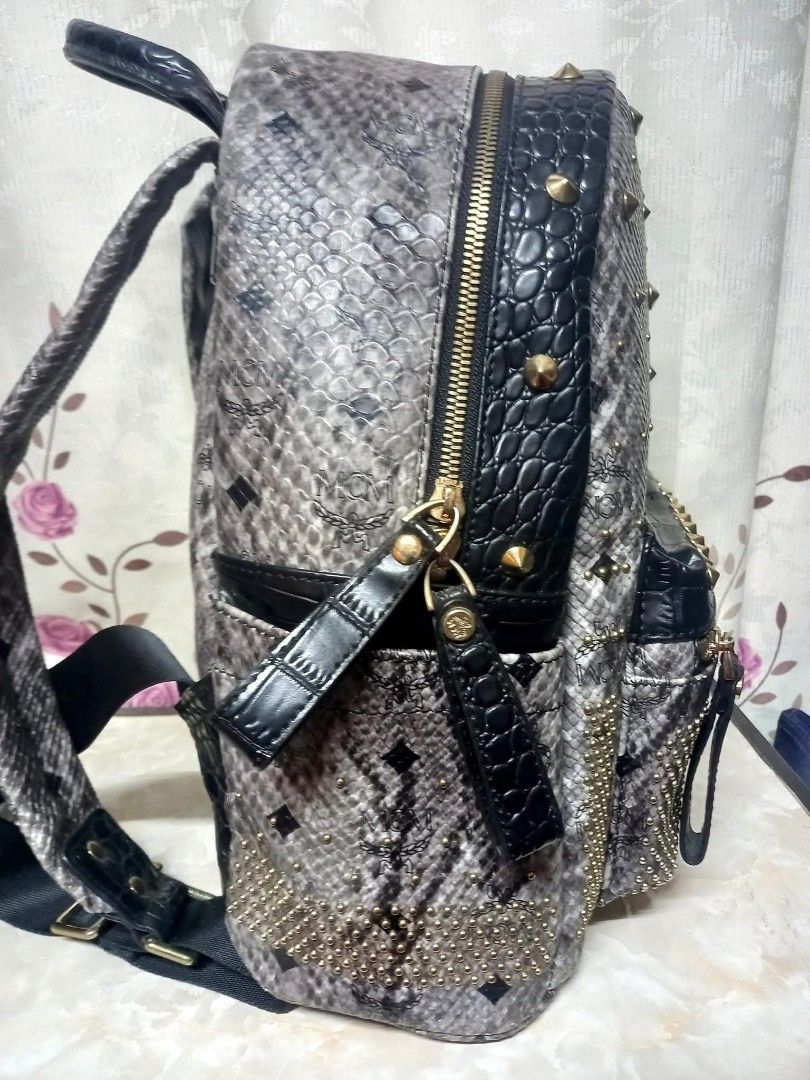 MCM Stark Studded Python Print Backpack (Category: Bags & Wallets) located in Semporna. Submitted by ummicollectionbundle (Listing ID 1465296379, Image 3). Description: URGENT SALE!!! - Brand: MCM - Design: Grey python print with all-over crystals and studs on front and sides - Accents: Black patent leather on front pocket and gold-tone hardware with iconic MCM logo plate - Features: Secure zipper closure, sturdy top handle, and adjustable should