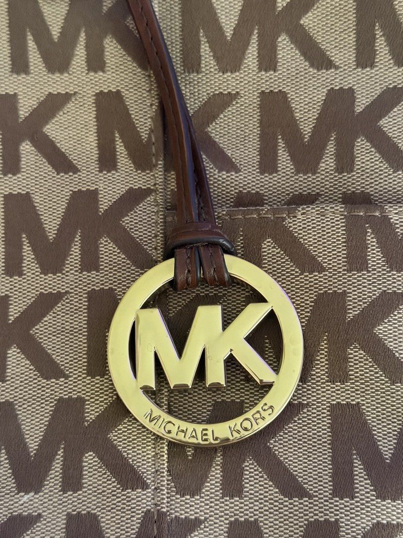 Michael Kors MK Monogram Brown Bag (Category: Shoulder Bags) located in Las Pinas. Submitted by kitkat333_ (Listing ID 1465314385, Image 2). Description: - Authentic Michael Kors tote in classic brown monogram - Elegant dark brown leather straps and gleaming gold-tone hardware, complete with MK charm - Intact leather - No stains/Signs of usage! - Secure top-zip closure to keep your belongings safe - Spacious fabric-lined interior with a middle zi