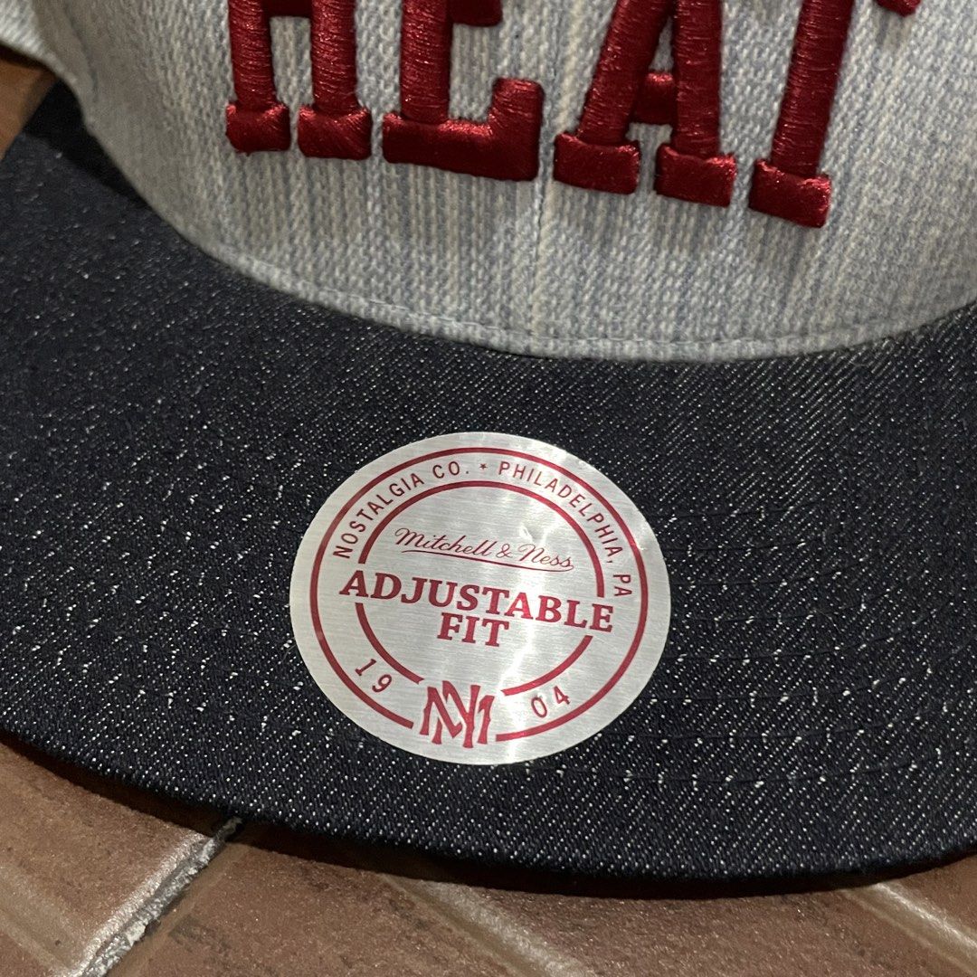 Mitchell & Ness Miami Heat Striped Snapback Cap (Category: Caps & Hats) located in Porac. Submitted by good.thriftsph (Listing ID 1465274609, Image 2). Description: - Brand: Mitchell & Ness - Team: Miami Heat - Design: Light grey textured striped crown with a dark denim brim - Embroidery: Red 'HEAT' text on the front and team logo on the side - Details: Mitchell & Ness script logo at the back, adjustable plastic strap, and original round sticker 