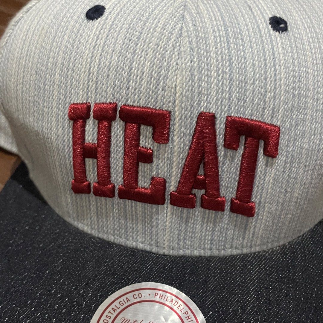 Mitchell & Ness Miami Heat Striped Snapback Cap (Category: Caps & Hats) located in Porac. Submitted by good.thriftsph (Listing ID 1465274609, Image 3). Description: - Brand: Mitchell & Ness - Team: Miami Heat - Design: Light grey textured striped crown with a dark denim brim - Embroidery: Red 'HEAT' text on the front and team logo on the side - Details: Mitchell & Ness script logo at the back, adjustable plastic strap, and original round sticker 