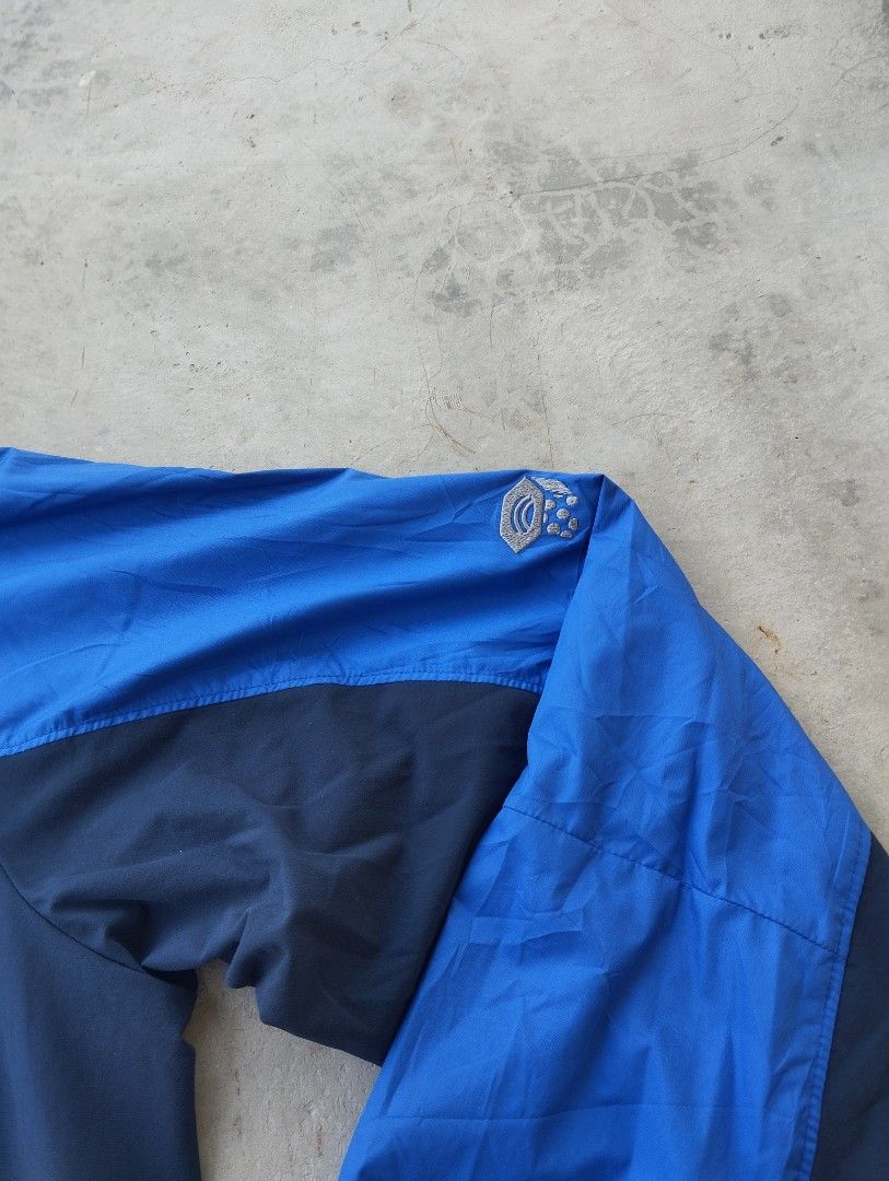 Mountain Hardwear Blue Windbreaker Jacket Size M (Category: Coats, Jackets and Outerwear) located in Mati. Submitted by old_era.ph (Listing ID 1465171782, Image 3). Description: - Brand: Mountain Hardwear - Size: M (Fits true to size) - Color: Bright blue and dark navy panels with black lining - Features: Stand collar, embroidered logos on chest and shoulder, vertical chest pocket, two zippered hand pockets, and adjustable drawstring hem - Origin