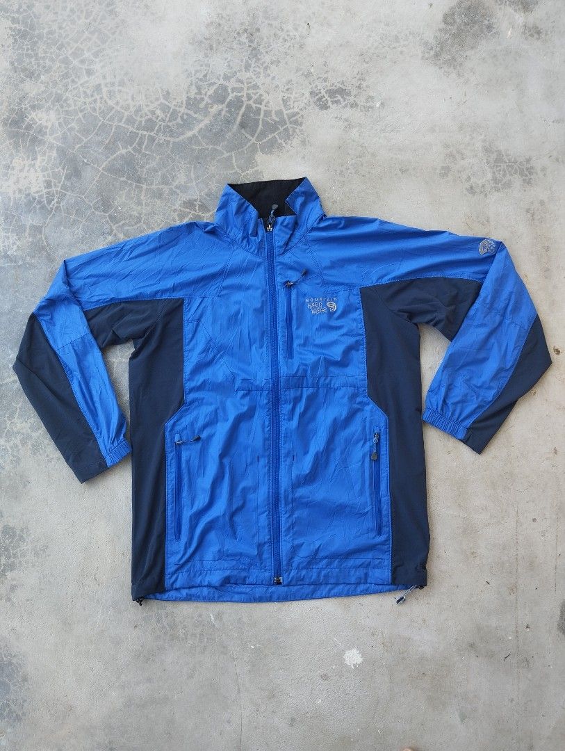 Mountain Hardwear Blue Windbreaker Jacket Size M (Category: Coats, Jackets and Outerwear) located in Mati. Submitted by old_era.ph (Listing ID 1465171782, Image 1). Description: - Brand: Mountain Hardwear - Size: M (Fits true to size) - Color: Bright blue and dark navy panels with black lining - Features: Stand collar, embroidered logos on chest and shoulder, vertical chest pocket, two zippered hand pockets, and adjustable drawstring hem - Origin