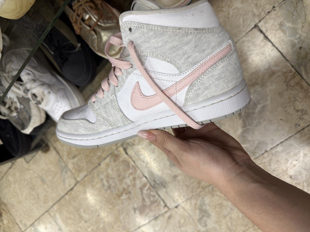 Nike Air Jordan 1 Mid Grey Pink (Category: Sneakers) located in Abucay. Submitted by fastlion.584bdf (Listing ID 1465361613, Image 3). Description: - Brand: Nike Air Jordan 1 Mid - Colorway: White leather base with cozy grey fleece overlays and pastel pink accents (Swoosh, laces, and branding) - Size: 235 / 2.5 (fits approx. US 4Y / EUR 35.5) - Condition: Clean overall, very minimal wear on soles - Features: Classic basketball shoe design with a 