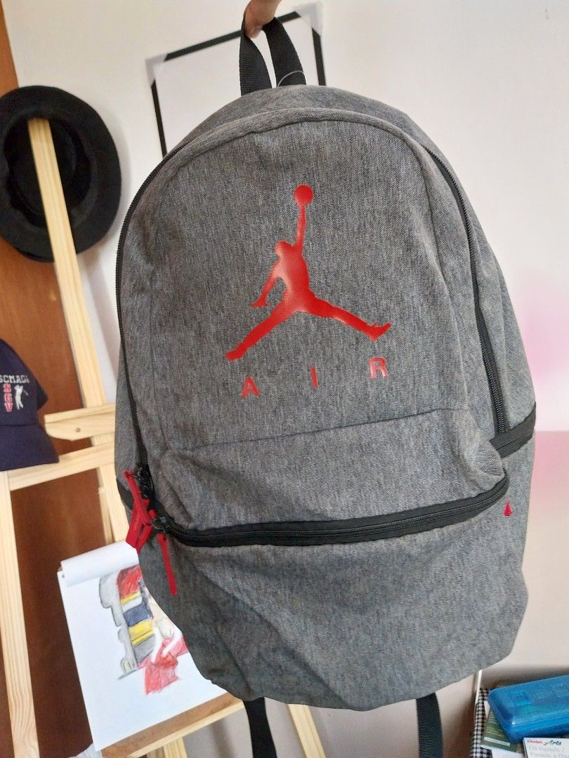Nike Air Jordan Jumpman bag (Category: Backpacks) located in Manila. Submitted by j.dlh (Listing ID 1465180769, Image 1). Description: - Color/Material: Grey heather fabric, 100% polyester (Made in Indonesia) - Branding: Large red Jumpman logo on front, smaller one on shoulder strap - Storage: Spacious main compartment with secure zip closure and front accessory compartment - Comfort: Padded mesh back panel and shoulder straps for all-day wear - 