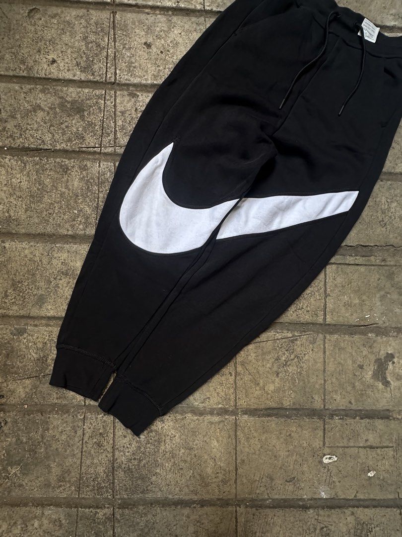 Nike Big Swoosh Black Sweatpants (Category: Joggers) located in Lapu Lapu. Submitted by gabocamaon03138 (Listing ID 1465236259, Image 2). Description: - Brand: Nike - Color: Black with giant white wrap-around Swoosh logo - Size: XS - Material: Super comfy fleece lining - Features: Adjustable drawstring waistband, ribbed ankle cuffs, and a right-side back pocket - Condition: Excellent / Ready to wear - Perfect for: Casual lounging, gym, or streetw