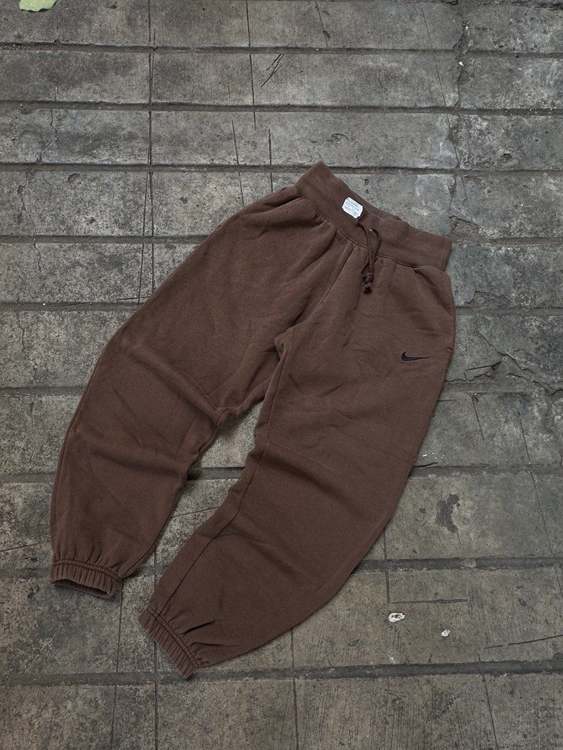 Nike Brown Joggers Sweatpants (Category: Joggers) located in Lapu Lapu. Submitted by gabocamaon03138 (Listing ID 1465236452, Image 3). Description: - Color: Brown - Brand: Nike - Fit: Relaxed baggy fit through the legs - Details: Small embroidered black swoosh logo on the left hip - Waistband: Adjustable drawstring with thick ribbed waist - Cuffs: Ribbed cuffs at the ankles - Condition: Super comfortable everyday loungewear.
