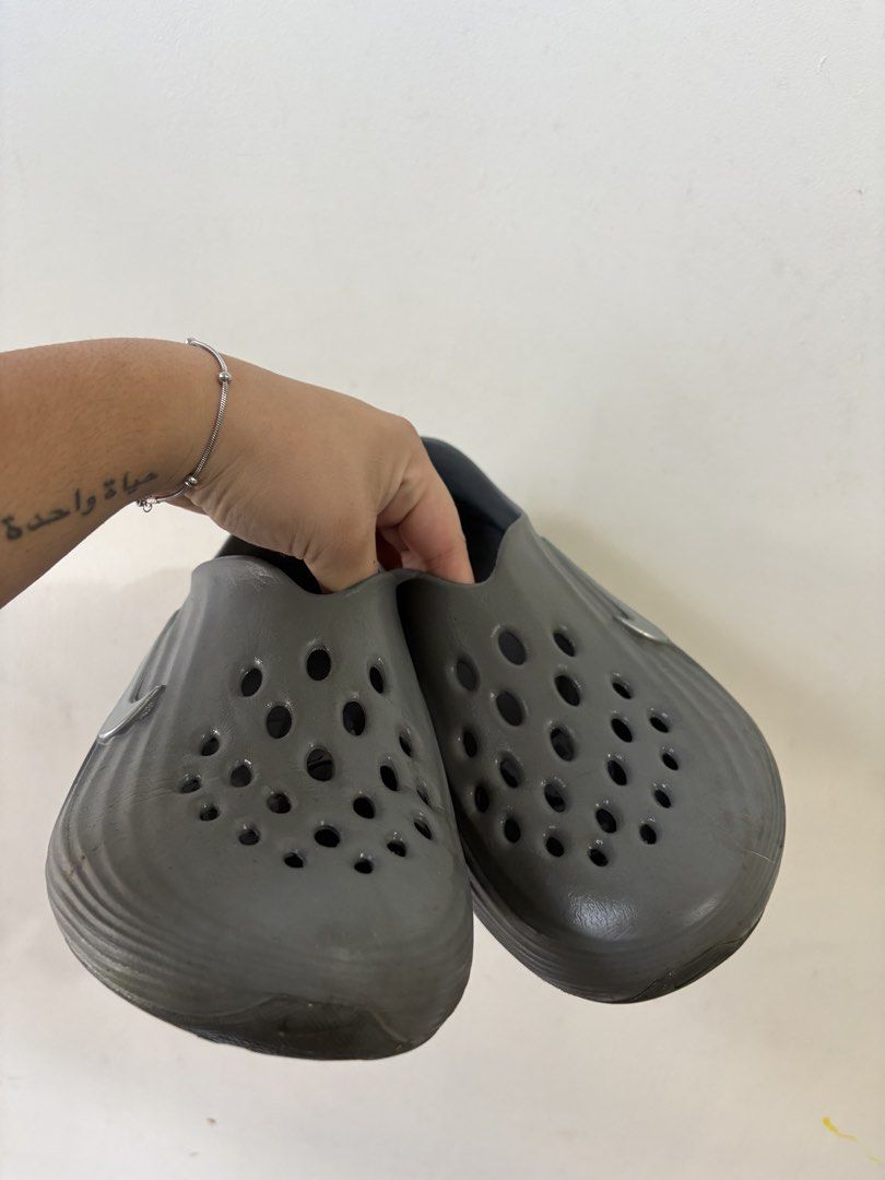 Nike Reactx (Category: Slippers & Slides) located in Manila. Submitted by roccolini (Listing ID 1465233160, Image 2). Description: - Color: Grey - Style: Slip-on clogs with ventilation holes for breathability - Design: Wavy ridged texture on sides and back heel with metallic silver Nike swoosh - Sole: Textured circular pattern for grip - Material: Comfortable, water-friendly, and easy to clean - Condition: Brand new / Great for everyday use 100% 