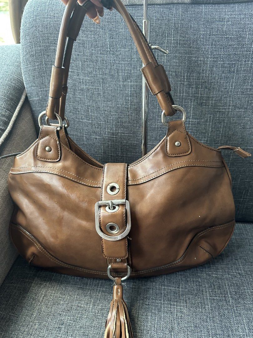 Nine West Brown Shoulder Bag with Tassel (Category: Shoulder Bags) located in Manila. Submitted by goldenhorse-dafc (Listing ID 1465376100, Image 1). Description: - Brand: Nine West - Material: Polyurethane (Brown) - Closure: Zip top - Hardware: Silver-tone - Details: Front buckle and cute hanging tassel - Interior: Fabric-lined with multiple pockets for organization - Flaw: Material peeling on the strap handles (priced accordingly).