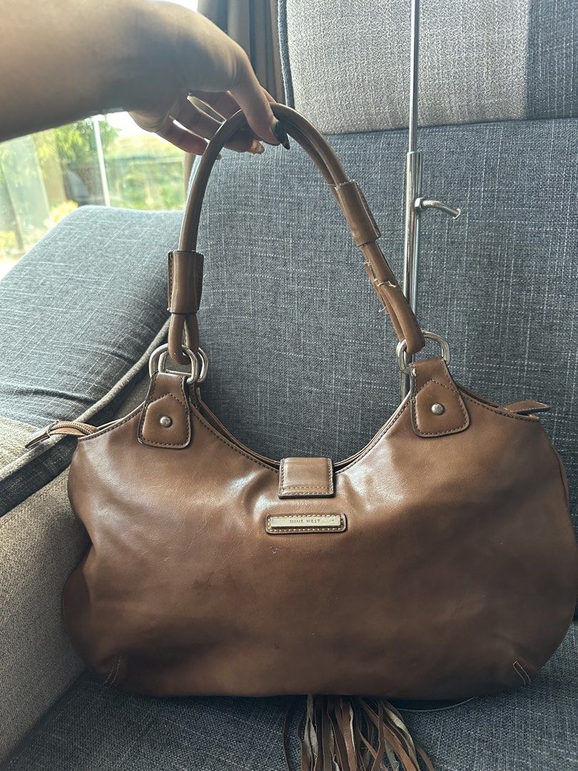 Nine West Brown Shoulder Bag with Tassel (Category: Shoulder Bags) located in Manila. Submitted by goldenhorse-dafc (Listing ID 1465376100, Image 3). Description: - Brand: Nine West - Material: Polyurethane (Brown) - Closure: Zip top - Hardware: Silver-tone - Details: Front buckle and cute hanging tassel - Interior: Fabric-lined with multiple pockets for organization - Flaw: Material peeling on the strap handles (priced accordingly).