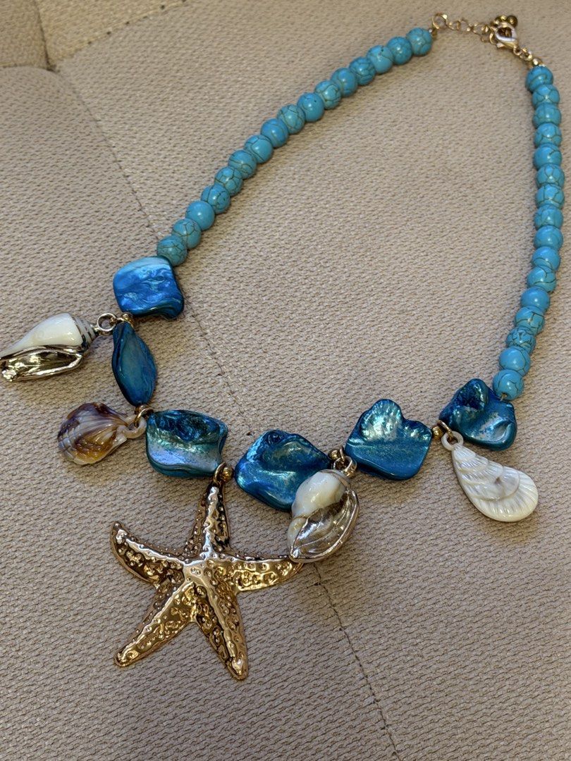 Ocean Beach Blue Turquoise Starfish Shell Pendant Statement Necklace (Category: Necklaces) located in Pasig City. Submitted by miss_abuelita (Listing ID 1465259991, Image 2). Description: Chunky blue turquoise beaded necklace with nautical charms. Features a large hammered gold starfish pendant, plus dangling seashells and mother-of-pearl style stones. Adjustable chain with lobster clasp closure. Total length sits around the collarbone. Great sta
