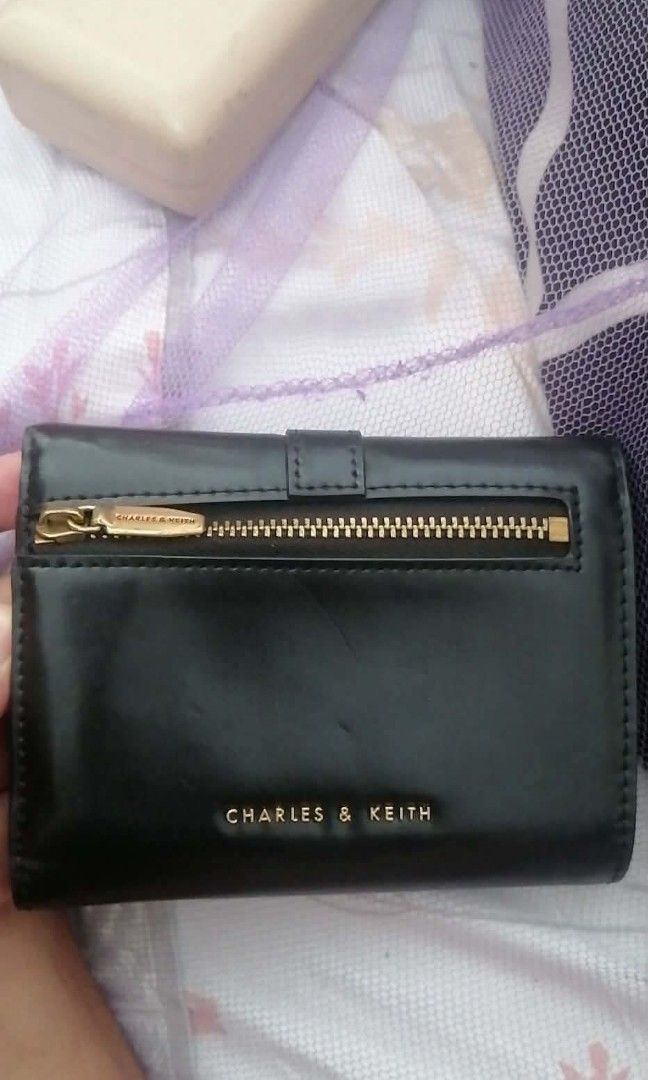 Original Charles & Keith Black Tri-fold Wallet - 100% Authentic (Category: Wallets & Card holders) located in Manila. Submitted by roseannlmn66895 (Listing ID 1464235567, Image 2). Description: *CHARLES & KEITH Wallet - Black* Tri-fold long wallet, black color, gold buckle and gold zipper. Faux leather, makinis, no bakbak. May card slots, bill compartment, coin zipper. With CHARLES & KEITH engrave sa zipper at emboss sa loob. Good as new, malinis