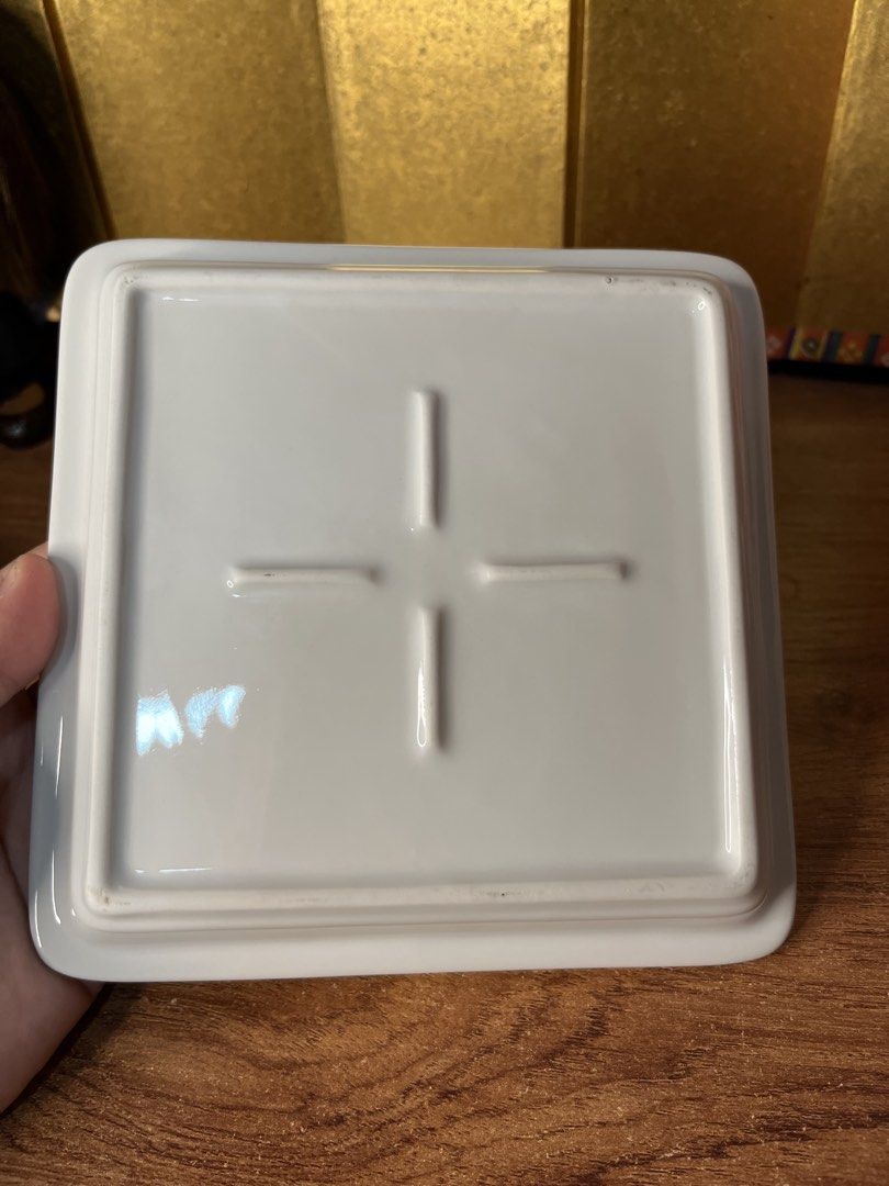 Original Sanrio Hello Kitty Ceramic Square Plate Tray (Category: Dinnerware & Cutlery) located in Gapan. Submitted by lunashop14 (Listing ID 1465175945, Image 2). Description: - Authentic Sanrio Kitty white ceramic square plate - Features a charming Kitty graphic with teacup and gift box illustrations - Dated '76, '05 Sanrio copyright near the bottom - Raised rim design with an indented cross pattern underneath - Finished with a smooth, glossy gl