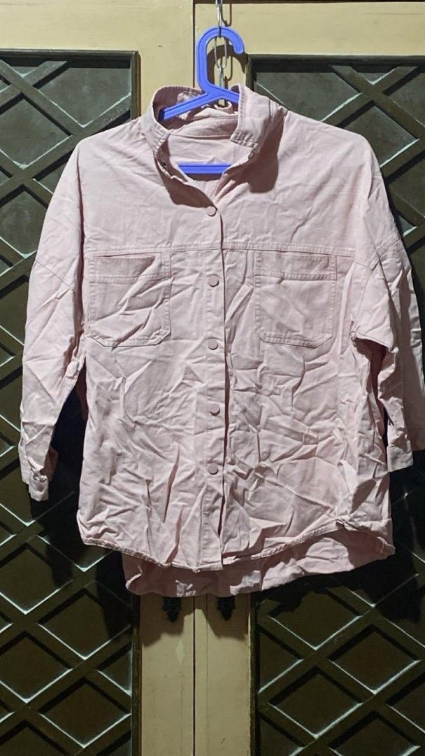 Pink Button-Up Long Sleeve Shirt with Pockets (Category: Longsleeves) located in Tarlac. Submitted by jieunieee (Listing ID 1465190302, Image 1). Description: - Color: Light pink - Fit: Relaxed fit with a standard shirt-tail hem - Details: Collared neckline, button-up front, and two functional chest pockets - Sleeves: Long sleeves with button cuffs - Fabric: Textured material, great for layering or wearing solo.