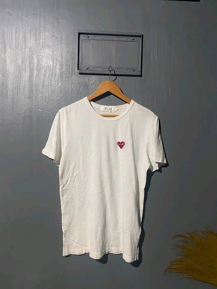 PLAY Comme des Garçons White Tee Size M (Category: Shirts) located in Manila. Submitted by bright.mayess (Listing ID 1465373375, Image 1). Description: - Brand: PLAY Comme des Garçons - Color: White - Size: Medium - Material: 100% Cotton, Made in Japan - Design: Classic red heart embroidery on left chest and big black PLAY logo printed on the back - Fit: Standard crew neck cut - Condition: Clean all around.