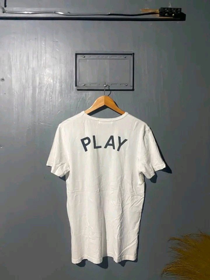 PLAY Comme des Garçons White Tee Size M (Category: Shirts) located in Manila. Submitted by bright.mayess (Listing ID 1465373375, Image 2). Description: - Brand: PLAY Comme des Garçons - Color: White - Size: Medium - Material: 100% Cotton, Made in Japan - Design: Classic red heart embroidery on left chest and big black PLAY logo printed on the back - Fit: Standard crew neck cut - Condition: Clean all around.