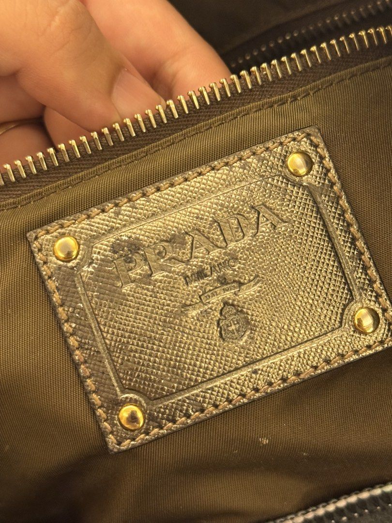 Prada Nylon Khaki Tote Bag (Authentic but restored) (Category: Tote Bags) located in Santa Rosa. Submitted by declutteredbyanna (Listing ID 1465214583, Image 3). Description: Authentic Prada tote bag - but the handle was restored to a gold handle (you can check the last pic for how it looked like before restoring) Bag needs cleaning and flaws shown in pictures so I’m selling it low Price still negotiable :) pm your offer.