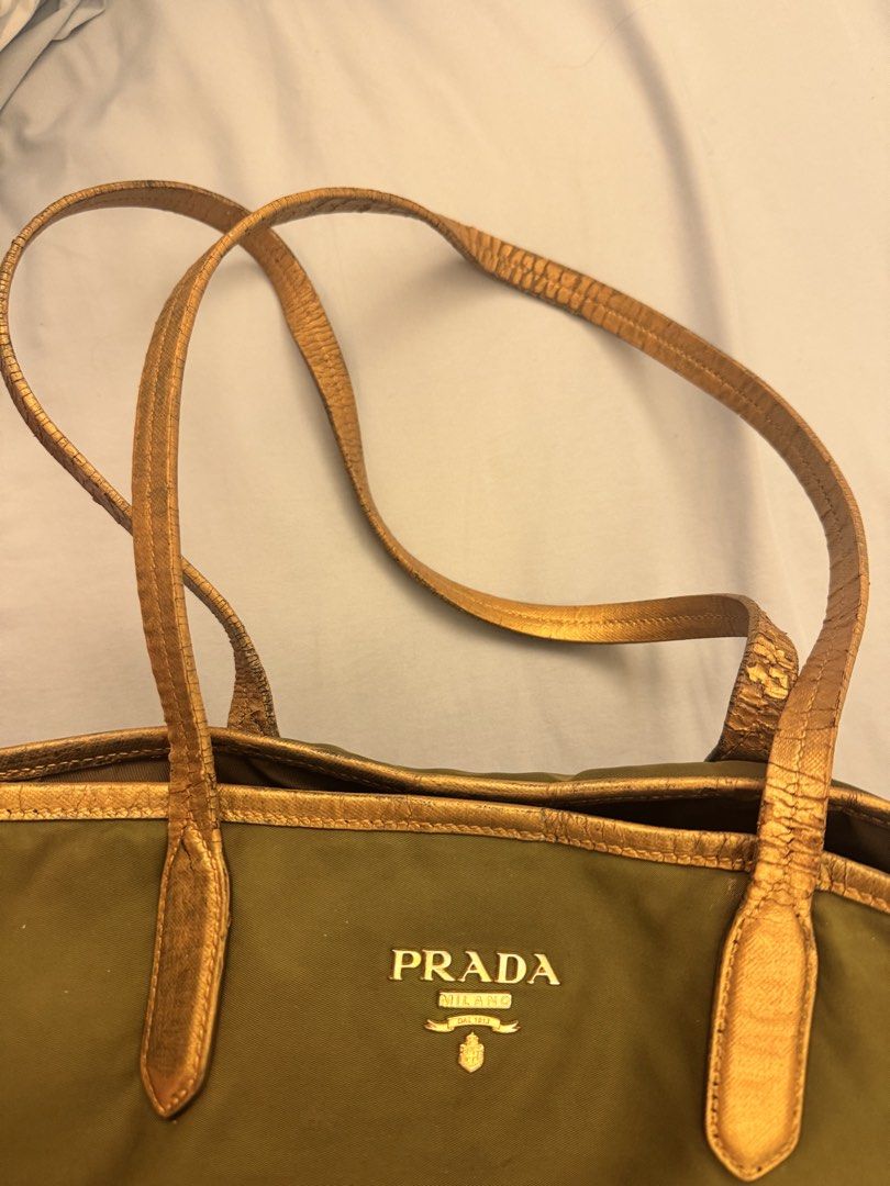 Prada Nylon Khaki Tote Bag (Authentic but restored) (Category: Tote Bags) located in Santa Rosa. Submitted by declutteredbyanna (Listing ID 1465214583, Image 2). Description: Authentic Prada tote bag - but the handle was restored to a gold handle (you can check the last pic for how it looked like before restoring) Bag needs cleaning and flaws shown in pictures so I’m selling it low Price still negotiable :) pm your offer.