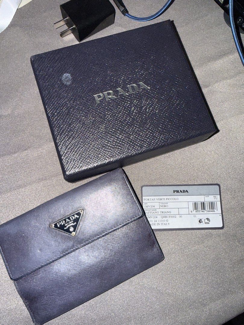Prada wallet (Category: Wallets & Card holders) located in Caloocan City. Submitted by rossvault2 (Listing ID 1465227058, Image 1). Description: - 100% Authentic Prada compact wallet in Nero Saffiano leather - Iconic enamel triangle logo plaque on the front flap - Secure snap button closure - Features multiple card slots and a spacious cash compartment - Crafted in Italy - Comes complete with original Prada box and authenticity card - Condition: 