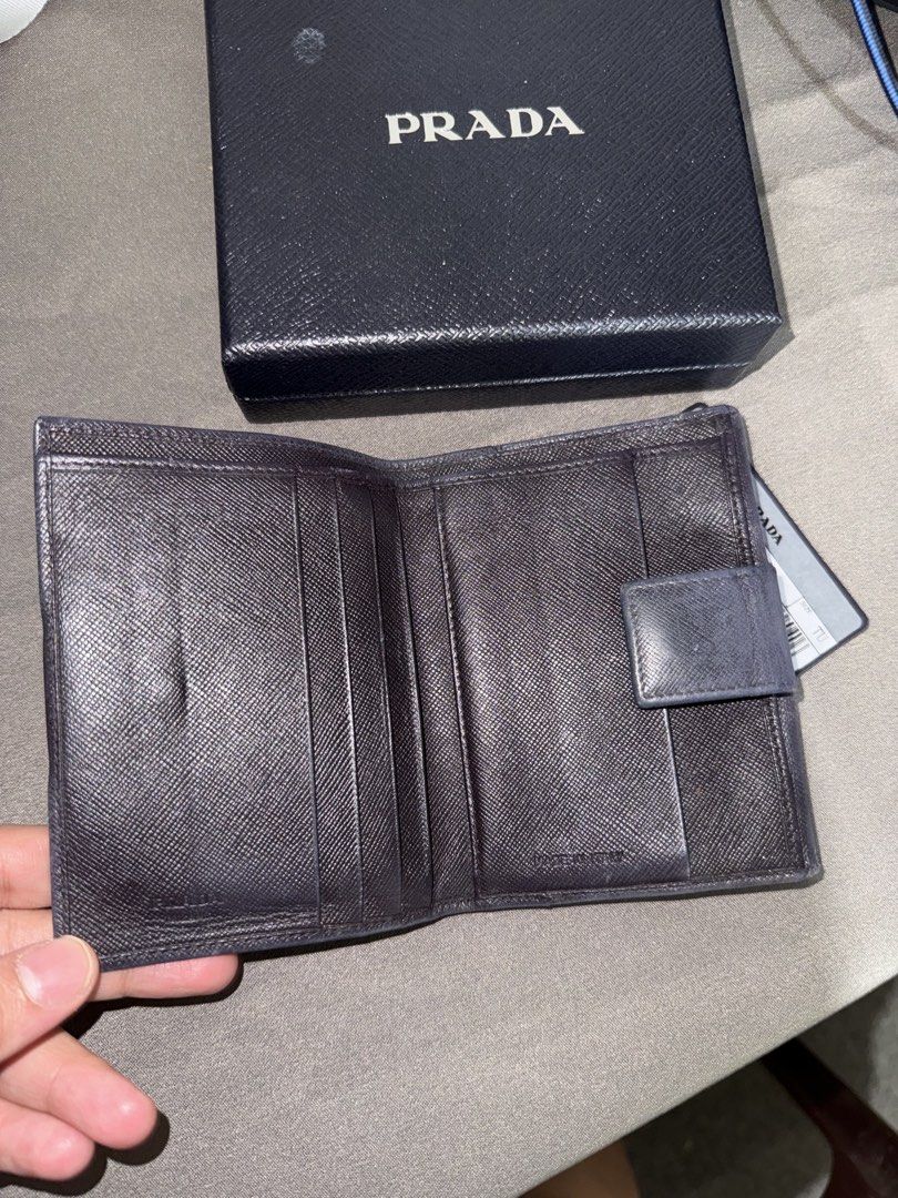 Prada wallet (Category: Wallets & Card holders) located in Caloocan City. Submitted by rossvault2 (Listing ID 1465227058, Image 2). Description: - 100% Authentic Prada compact wallet in Nero Saffiano leather - Iconic enamel triangle logo plaque on the front flap - Secure snap button closure - Features multiple card slots and a spacious cash compartment - Crafted in Italy - Comes complete with original Prada box and authenticity card - Condition: 