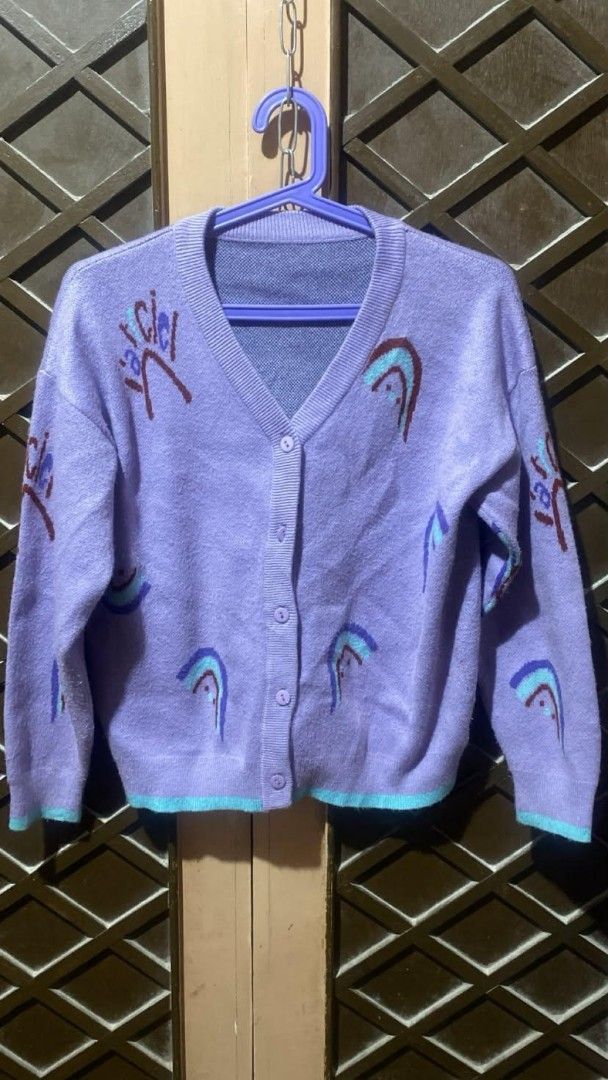 Purple knitted cardigan with abstract rainbow patterns (Category: Coats, Jackets and Outerwear) located in Tarlac. Submitted by jieunieee (Listing ID 1465195981, Image 1). Description: - Color: Light purple with colorful abstract patterns - Details: V-neck cut, front button closure, blue trim on bottom hem and sleeve cuffs - Material: Soft, cozy knit - Fit: Long sleeves, easy to layer over tees or tanks - Condition: Brand new / Excellent quality 