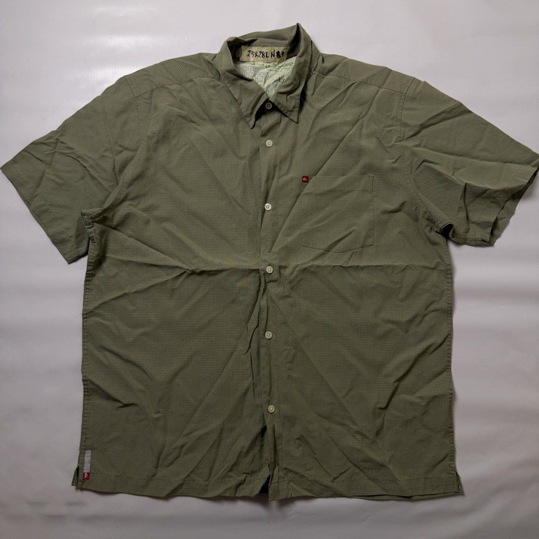 Quiksilver Green Button-Down Short Sleeve Shirt (Category: Tshirts & Polo Shirts ) located in Manila. Submitted by johnedel_james (Listing ID 1465263095, Image 1). Description: - Brand: Quiksilver - Color: Olive Green with textured grid pattern - Style: Short-sleeve button-down shirt with standard collar - Details: Single chest pocket with red logo tag, hem and inner collar branding - Material: 70% polynosic rayon, 30% polyester - Care: Machine w