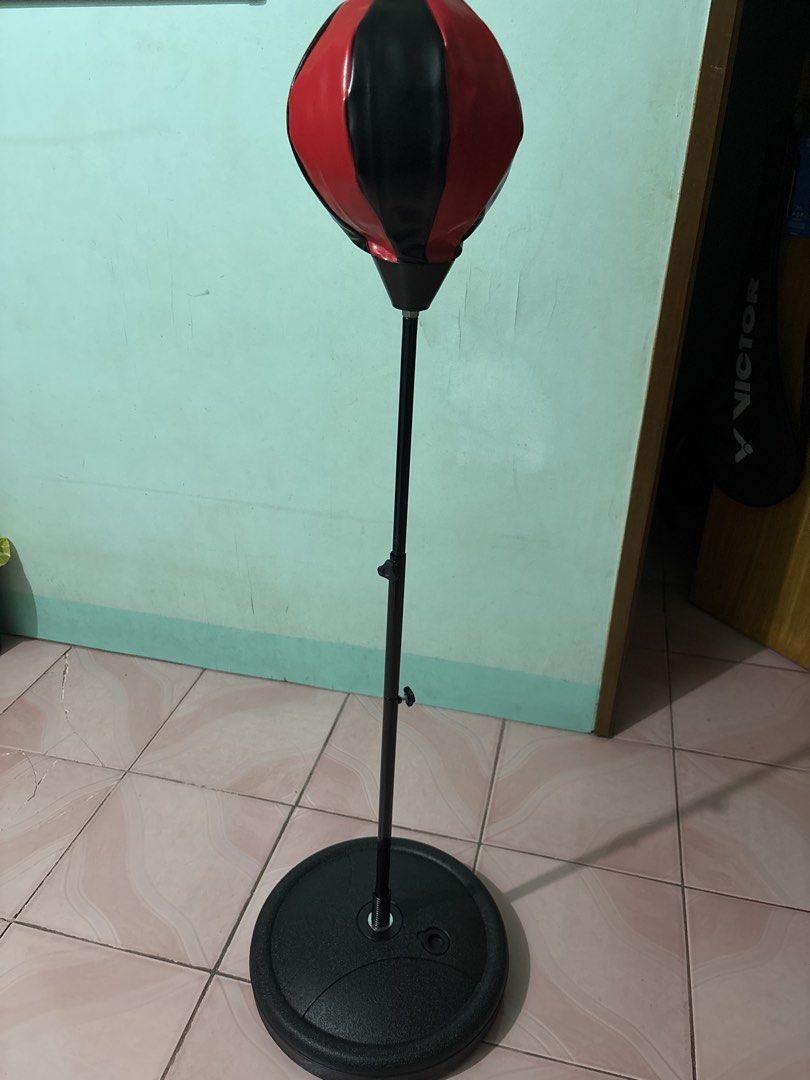 Red and black standing speed bag with adjustable height (Category: Combat Sports) located in Binan City. Submitted by fashion_claims (Listing ID 1465246765, Image 3). Description: - Type: Standing speed bag for boxing, cardio, and home workouts - Material: Red and black leatherette punching ball with a metal spring base - Adjustable: Height-adjustable pole equipped with two secure tightening knobs - Base: Heavy-duty black plastic base; fillable w