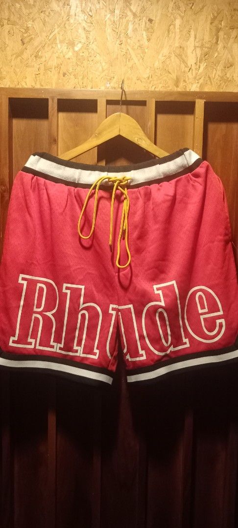 Rhude Red Basketball Shorts (Category: Shorts) located in Manila. Submitted by worldgearph (Listing ID 1465272141, Image 1). Description: - Brand: Rhude - Color: Red with white, black, and yellow accents - Material: Breathable mesh - Details: White and black striped waistband, striking yellow drawstrings, large white Rhude front print - Pockets: Two functional back flapped pockets - Hem: Black and white trim along the bottom - Condition: Tagged i