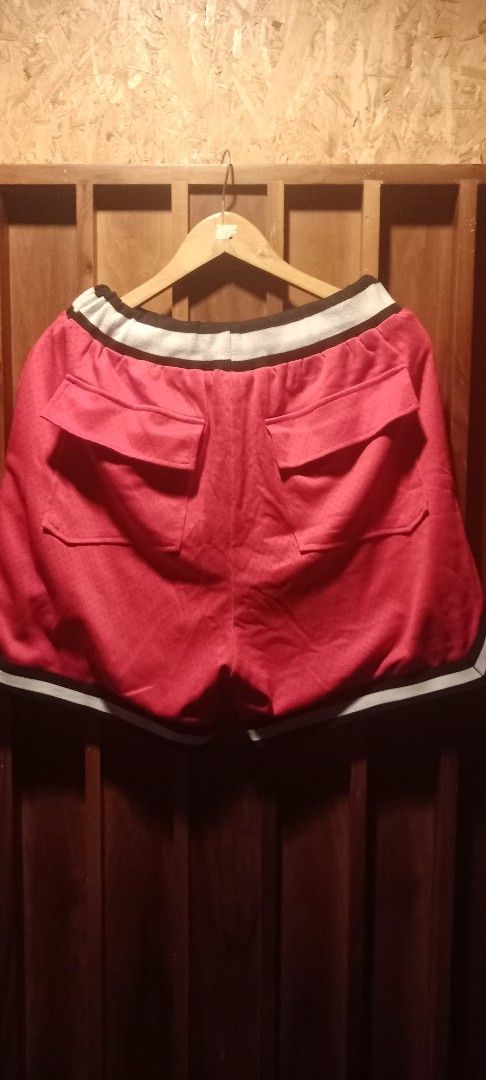Rhude Red Basketball Shorts (Category: Shorts) located in Manila. Submitted by worldgearph (Listing ID 1465272141, Image 2). Description: - Brand: Rhude - Color: Red with white, black, and yellow accents - Material: Breathable mesh - Details: White and black striped waistband, striking yellow drawstrings, large white Rhude front print - Pockets: Two functional back flapped pockets - Hem: Black and white trim along the bottom - Condition: Tagged i