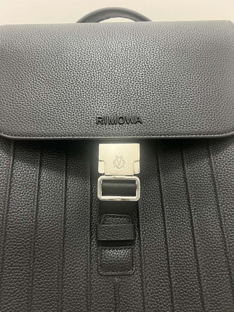 RIMOWA Black Leather Backpack (Category: Backpacks) located in Paoay. Submitted by rvf1230 (Listing ID 1465207589, Image 2). Description: - Brand: Rimowa - Material: Premium black grained leather with silver-tone hardware - Closure: Secure front buckle with flap top design - Storage: Two side zippered pockets and a clean interior layout - Comfort: Padded, adjustable shoulder straps and breathable mesh back panel - Portability: Convenient top hand