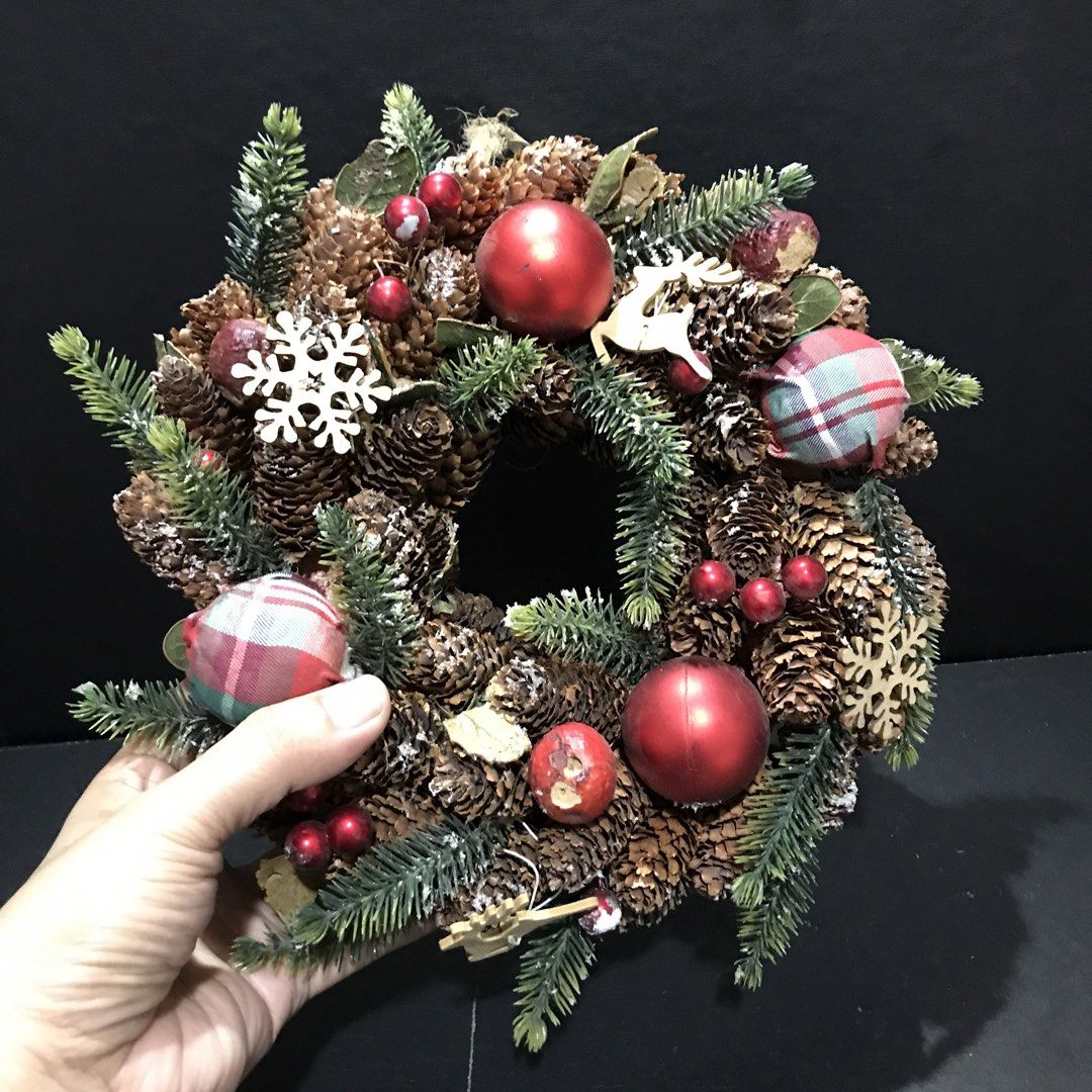 Rustic Christmas Pinecone Wreath with Plaid Ornaments (Category: Wall Decor) located in Baao. Submitted by all.things.japan (Listing ID 1465306696, Image 2). Description: 9.5 inches/24.0 cm diameter - Beautiful holiday wreath made with natural pinecones and evergreen needles - Decorated with shiny red baubles, plaid fabric balls, wooden snowflakes, and a charming wooden reindeer - Accented with scattered small red berries for a festive touch - St