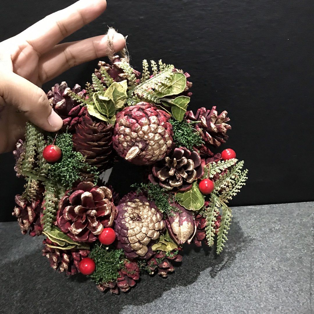 Rustic Christmas wreath with pinecones and red berries (Category: Wall Decor) located in Baao. Submitted by all.things.japan (Listing ID 1465310941, Image 3). Description: 7.0 inches/18 cm diameter - Festive holiday wreath crafted from natural pinecones - Beautiful burgundy and gold dipped tips - Decorated with lush green foliage, moss, and bright red berries - Includes a sturdy cardboard backing with tag attached - Equipped with a jute twine loo
