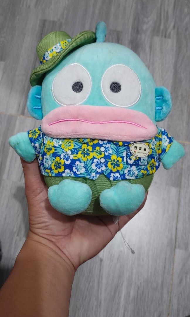 Sanrio Collab Hangyodon (Category: Designer & Blind Box Toys) located in Caloocan City. Submitted by cogeothriftapparel (Listing ID 1465296140, Image 1). Description: Limitted ! Sanrio collaboration plush of the character Hangyodon wearing an Amazon Express-themed floral shirt and a matching green hat..