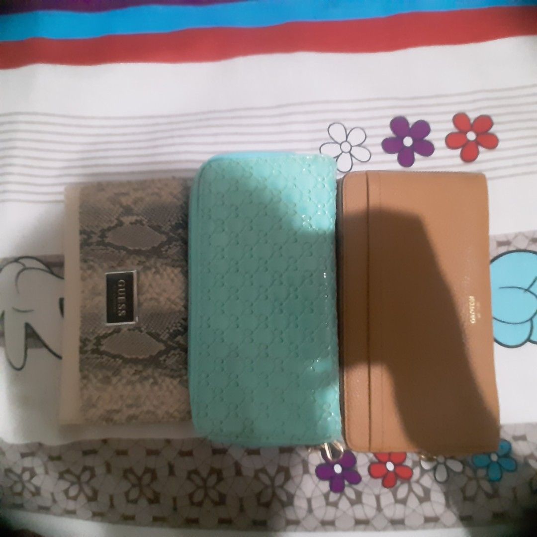Set of three wallets Guess and Ganton (Category: Wallets & Card holders) located in Makati City. Submitted by johnjo6666 (Listing ID 1465309818, Image 1). Description: - 3-in-1 wallet bundle offering great variety for your daily rotation - Piece 1: Snakeskin pattern with Guess metal logo on the front - Piece 2: Mint green with an all-over debossed monogram pattern - Piece 3: Solid brown leather featuring external card slots - Condition: Clean ove