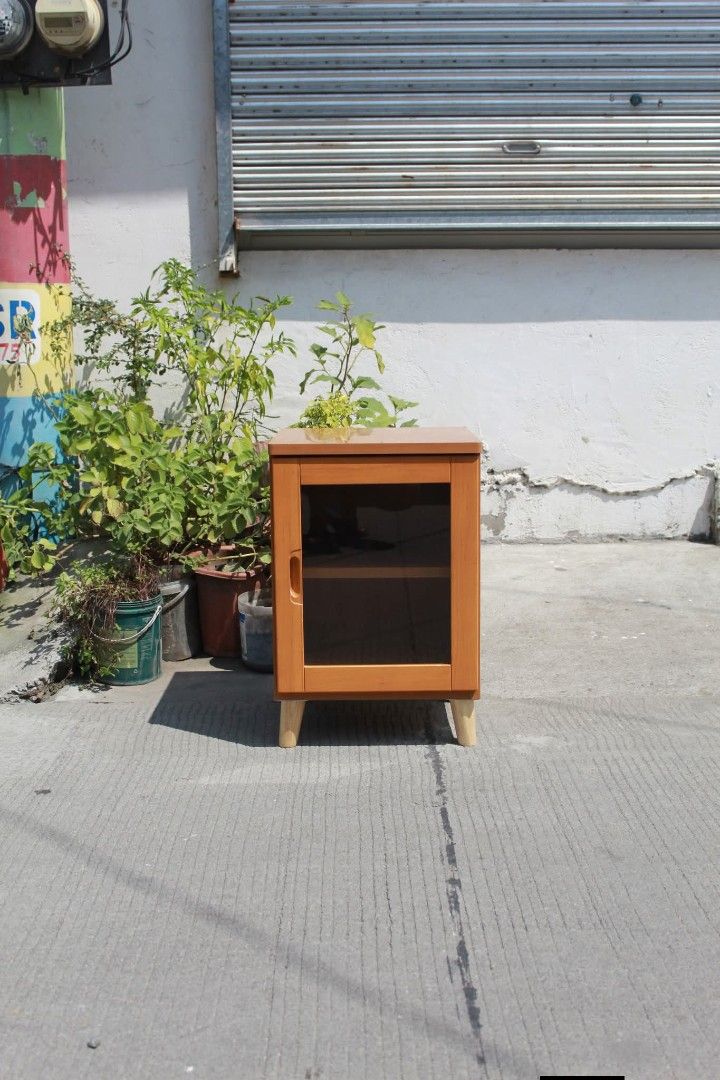 Side Cabinet (Category: Shelves, Cabinets & Racks) located in Meycauayan. Submitted by marygracecasimiro (Listing ID 1465173927, Image 1). Description: Compact Wooden Glass Cabinet Clear glass door, interior shelf, warm honey-cherry finish and tapered wooden legs. Perfect as a bedside table, side cabinet or small storage unit L:15 ¾ • W:15 ¾ • H:24 inches 4,000 pesos only🩷🧡.