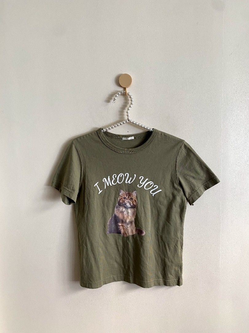 Small - GU Printed Cat Shirt (Category: Others Tops) located in Castillejos. Submitted by lalainecloset22 (Listing ID 1465206824, Image 2). Description: - Brand: GU (Uniqlo group) - Size: S (155/80A) - Color: Moss Green - Material: 100% Cotton, soft and breathable - Design: 'I meow you' text with cute printed cat graphic - Condition: Excellent pre-loved condition - Perfect casual tee for cat lovers and daily outfit rotation.