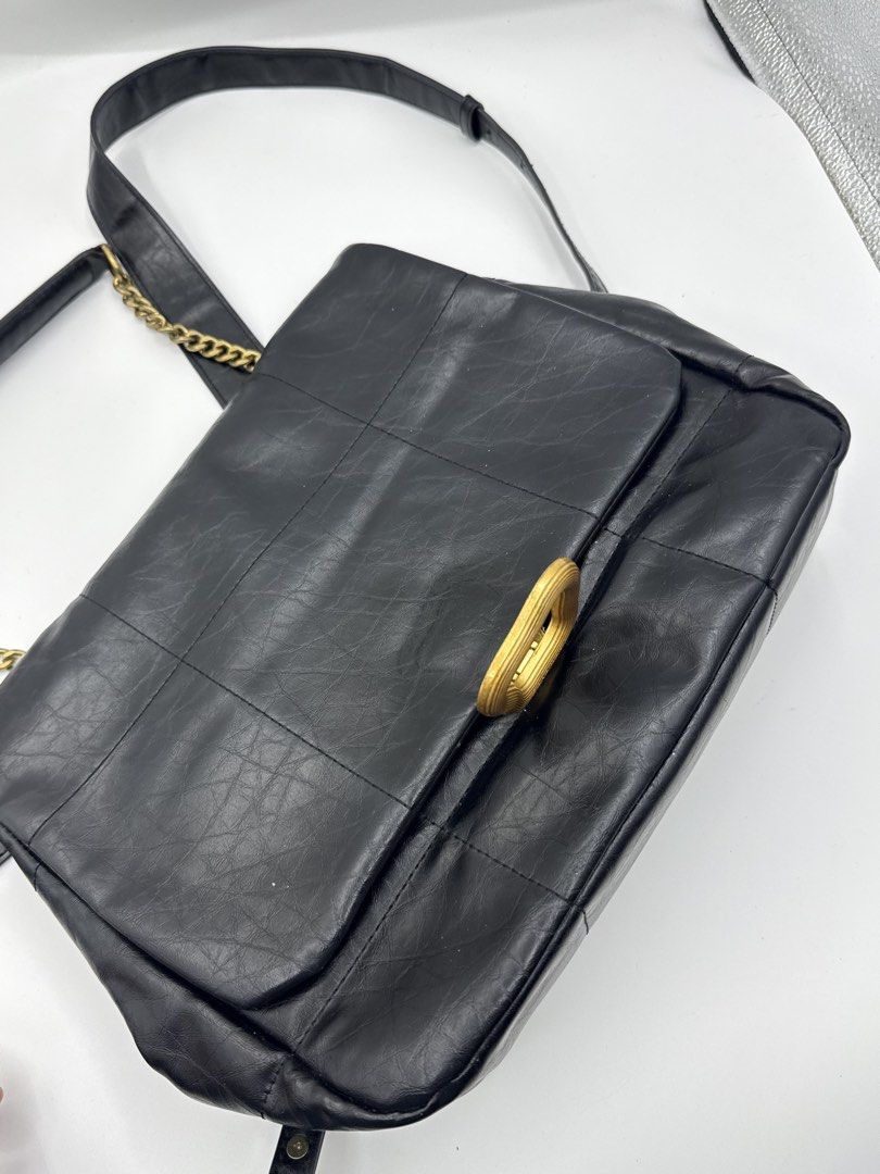 Songmont (Category: Backpacks) located in Caloocan City. Submitted by rossvault2 (Listing ID 1465230883, Image 3). Description: - Style: Structured boxy shoulder bag with chic black quilted design - Hardware & Closure: Bold gold-tone statement buckle on front flap - Strap: Adjustable chain and leather combo for versatile carry lengths - Interior: Vibrant contrasting red lining with inner slip pockets and a secure zippered compartment - Capacity: 