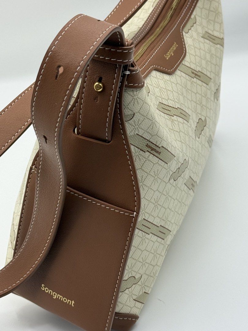 Songmont (Category: Shoulder Bags) located in Caloocan City. Submitted by rossvault2 (Listing ID 1465240682, Image 3). Description: - Brand: authentic Songmont - Color: Cream and brown with monogram pattern - Material: Canvas body with brown leather trim - Hardware: Gold-tone - Closure: Top zip - Strap: Adjustable shoulder strap - Base: Structured rectangular base with leather reinforcement - Details: Clean stitching throughout.