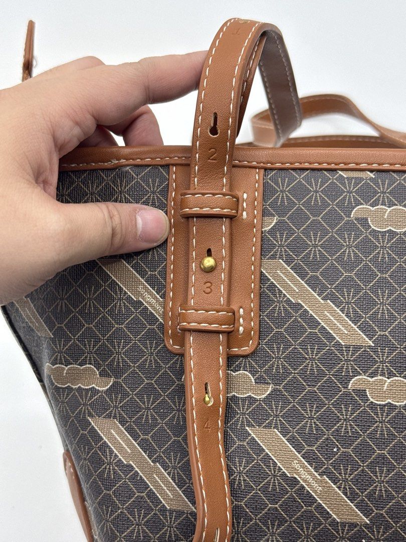 Songmont Monogram Cloud Tote Bag Brown (Category: Tote Bags) located in Caloocan City. Submitted by rossvault2 (Listing ID 1465242226, Image 3). Description: - Brand: Songmont Tote Bag - Design: Brown monogram print with cloud patterns and tan leather trim - Straps: Dual shoulder straps with adjustable numbered loops - Base: Protective metal feet for durability - Extras: Includes matching tan leather luggage tag with gold debossed logo - Shape: S