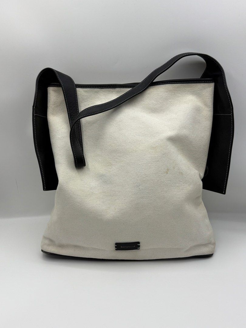 Songmont Tote Bag (Category: Tote Bags) located in Caloocan City. Submitted by rossvault2 (Listing ID 1465234996, Image 1). Description: - Brand: authentic Songmont Tote Bag - Material: Cream canvas with black leather trim, bottom panel, and matching shoulder strap - Details: Gold-foil brand stamp on the side tab and dark embossed label patch on the front - Condition: Pre-loved with noticeable light stains on the cream canvas body (priced accordi