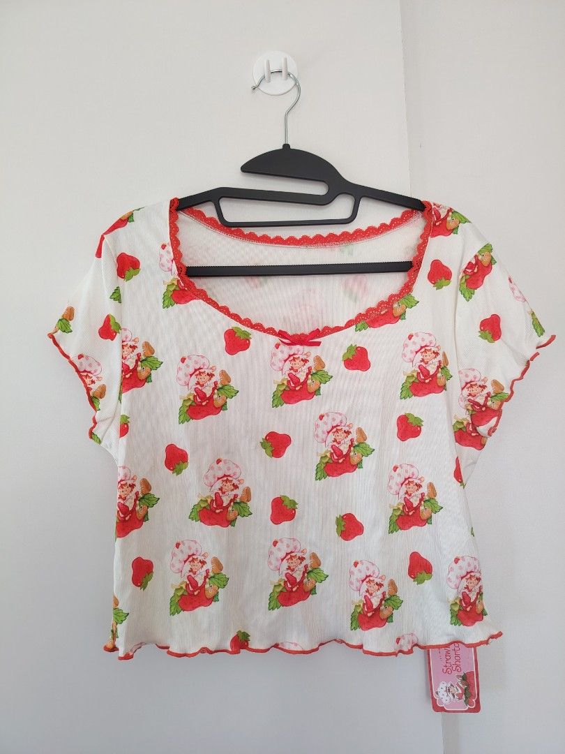 Strawberry Shortcake X SHEIN White Ribbed Top (Category: Shirts) located in Manila. Submitted by babeboxtheory (Listing ID 1465189237, Image 2). Description: - Official SHEIN x Strawberry Shortcake collaboration - Condition: Brand new with original tags attached - Size: 1XL - Design: White ribbed short-sleeve top with all-over Strawberry Shortcake print - Details: Scoop neckline with red lace trim, tiny center bow, and lettuce edge hem and sleeve