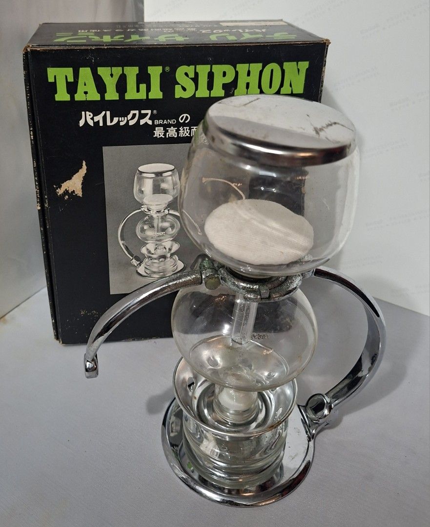 Tayli Siphon Mini Coffee Maker (Category: Coffee Machines & Makers) located in Manila. Submitted by glydelmalu86312 (Listing ID 1465309249, Image 2). Description: Tayli Siphon Mini vacuum coffee maker, glass chambers and chrome stand included. Original box included in the back. Burner and cloth filter assembly attached. Vintage piece, shows some tarnishing on the metal hardware from age. Glass is clear and intact. Great collector item for manual 
