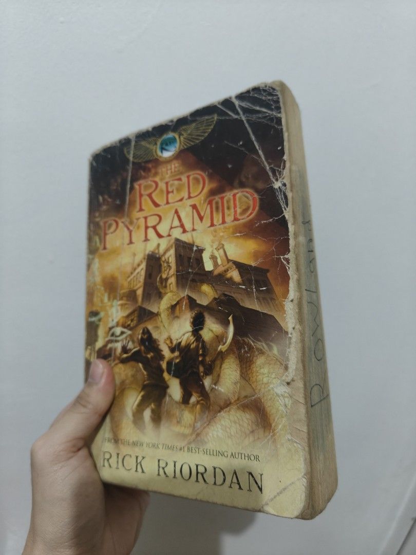 The Red Pyramid by Rick Riordan paperback (Category: Storybooks) located in Lubao. Submitted by fernandezcams (Listing ID 1465264233, Image 1). Description: - Title: The Red Pyramid (The Kane Chronicles #1) by Rick Riordan - Condition: Heavily used and reading copy only - Exterior: Major cover creasing, peeling edges, and yellowed pages - Flaws: Previous owner's name written in marker on the side page edge - Interior: Pages are complete and entir