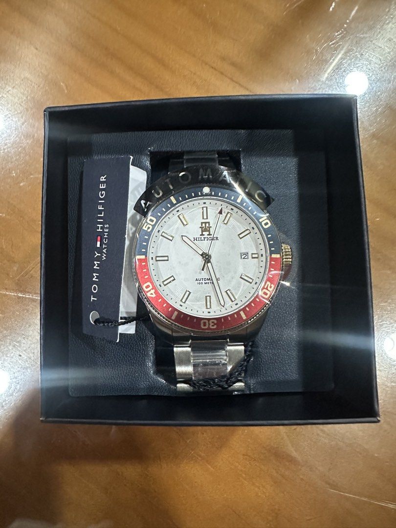 Tommy Hilfiger 1710551 Automatic Watch (Category: Men's Watches) located in Makati City. Submitted by akabry (Listing ID 1465295241, Image 1). Description: - Brand: Tommy Hilfiger - Movement: Automatic - Dial: White textured with a date window at 3 o'clock - Bezel: blue and red - Crown: Gold-tone with embossed H logo - Condition: Brand new, stainless steel bracelet still wrapped in protective seal/plastic Still negotiable! PM for Offers :).