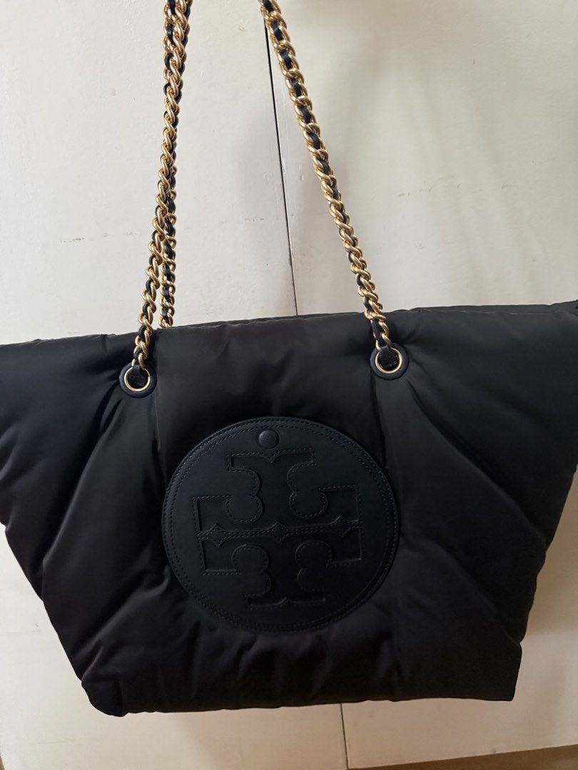 Tory Burch Black Puffer Tote Bag with Chain Straps (Category: Tote Bags) located in Cavite. Submitted by jd0217 (Listing ID 1465219951, Image 1). Description: - Brand: Tory Burch - Material: Black quilted puffer - Hardware: Gold chain shoulder straps woven with black leather - Design: Big round logo patch on the front - Capacity: Super roomy main compartment - Condition: Great everyday bag for all your daily essentials.