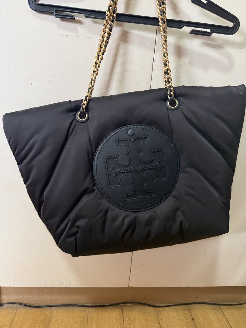 Tory Burch Black Puffer Tote Bag with Chain Straps (Category: Tote Bags) located in Cavite. Submitted by jd0217 (Listing ID 1465219951, Image 2). Description: - Brand: Tory Burch - Material: Black quilted puffer - Hardware: Gold chain shoulder straps woven with black leather - Design: Big round logo patch on the front - Capacity: Super roomy main compartment - Condition: Great everyday bag for all your daily essentials.