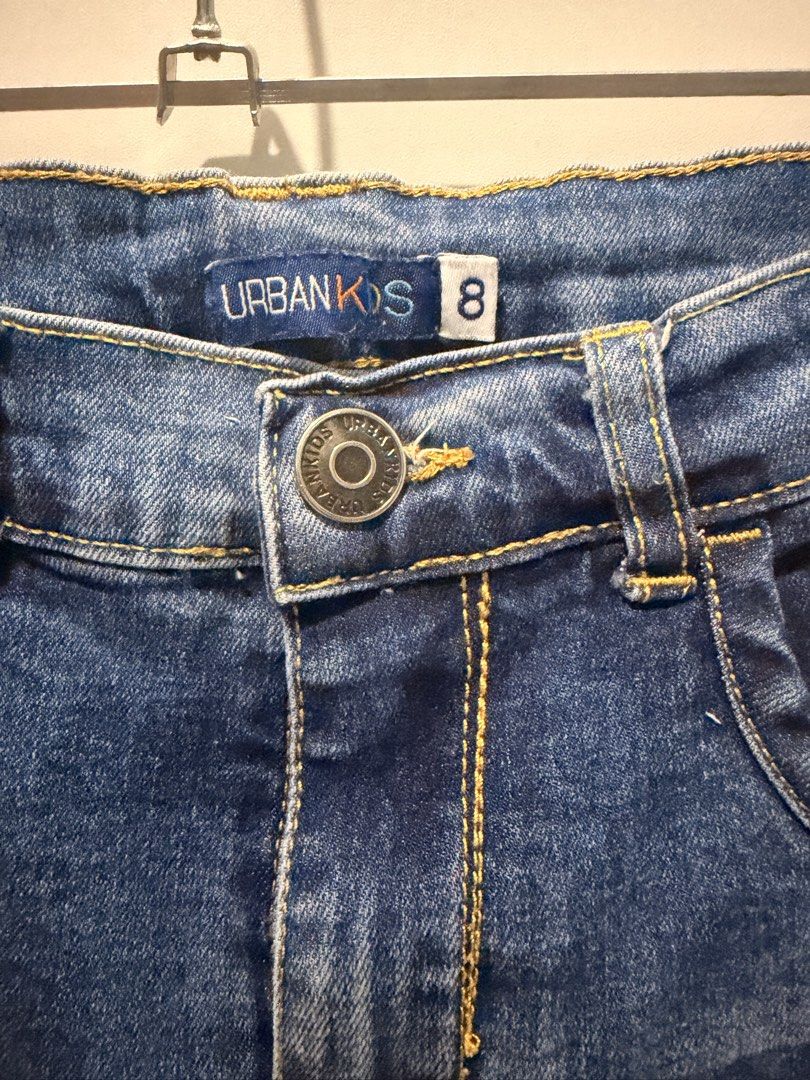 URBANKIDS Blue Denim Jeans Size 8 (Category: Babies & Kids Fashion) located in Las Pinas. Submitted by kleoshop24 (Listing ID 1465211974, Image 2). Description: - Brand: Urbankids - Size: 8 (Tag attached inside waistband) - Color: Classic blue denim with standard washing effect - Fit: Straight leg cut - Details: Button closure with zipper fly, classic 5-pocket layout, contrast yellow stitching, and small leather patch on the front pocket - Condit
